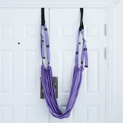 Stretch belt mounted over door with foam pads on rope ends, showing the attachment method, cushioning, and how the inverted rope pull design reduces friction on surfaces.